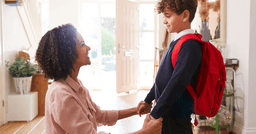 Mom holding preschool boys hand as he gets ready to leave for school