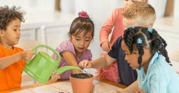 Group of preschoolers engaging in a science experiment as they pour water into a plant