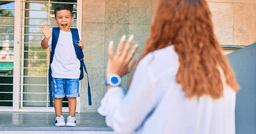 Mom waving goodbye to preschool boy on his first day of school