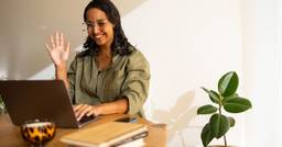 Childcare center parent waving at computer screen during online conference with center director