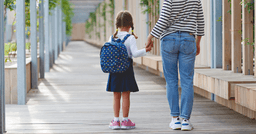 Parent holding preschool girls hand as they walk to their classroom on the first day of school