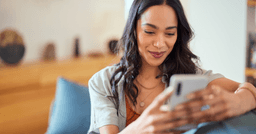 Childcare parent looking at phone and smiling as they receive updates on their childcare management app