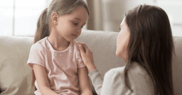 Teacher resting hand on little girl and comforting her