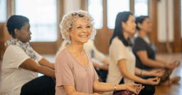 Woman smiling at yoga class with her colleagues
