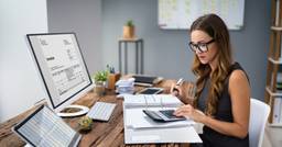 Childcare director sitting at computer and reviewing tuition invoices