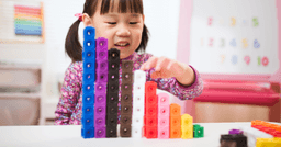Preschool girl stacking blocks by height and colour in her preschool classroom